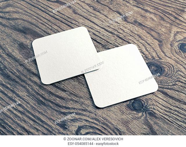 Photo of two blank white beer coasters on wood table background. Blank template for your design