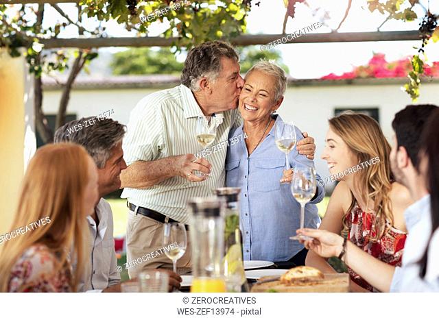 Happy senior couple with family having lunch together outside