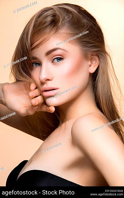 Beautiful young woman with perfect skin and loose hair. Beauty shot. Over beige background