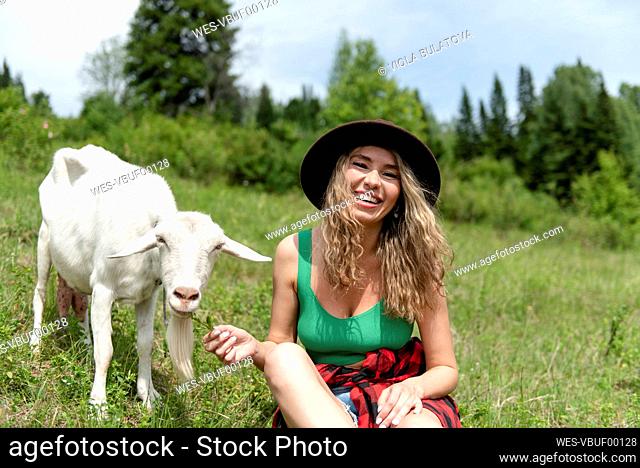 Happy woman feeding goat on mountain