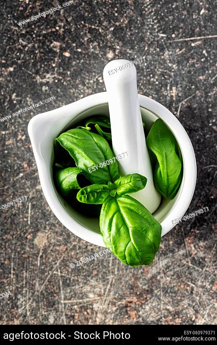 Fresh green basil leaves in a mortar. Top view