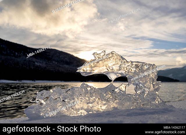 Ice during sunset on the shore of Walchensee lake in the Bavarian foothills of the Alps with sun rays