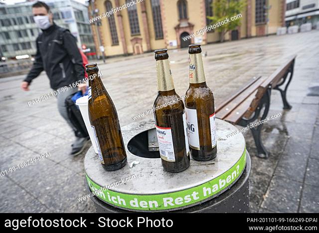 01 November 2020, Hessen, Frankfurt/Main: Empty beer bottles stand on a litter basket on the square ""An der Hauptwache"" in the city centre