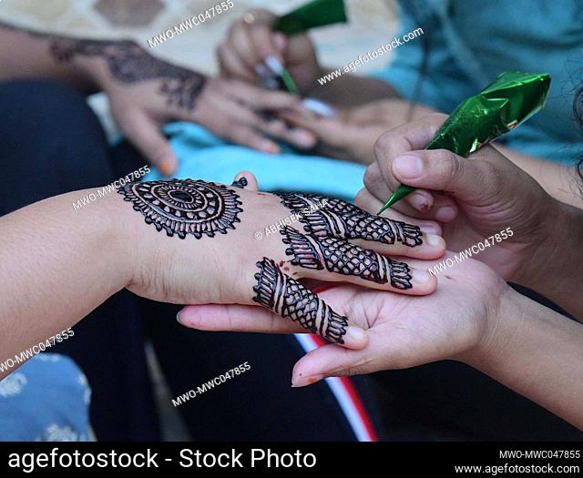 Girls get their hands decorated with traditional henna designs on the eve of Eid al-Fitr in Agartala. Trupura, India