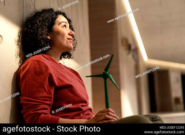 Smiling businesswoman with turbine looking up sitting in office corridor