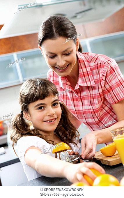 Mother and daughter squeezing oranges in a kitchen