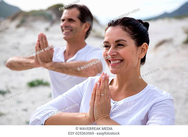 Couple performing yoga on beach