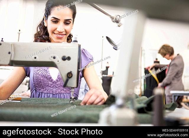 Smiling seamstress at work in a tailor shop