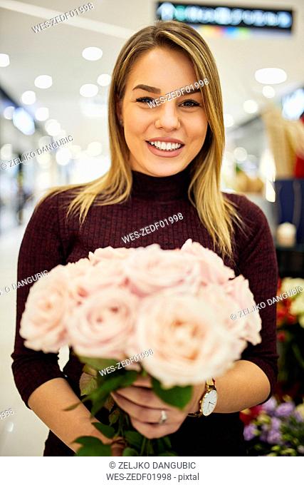 Portrait of smiling woman holding bunch of flowers in flower shop