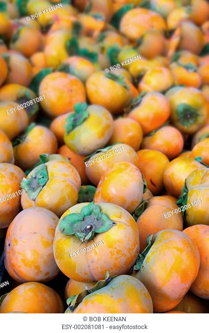 Pile of orange persimmons vertical