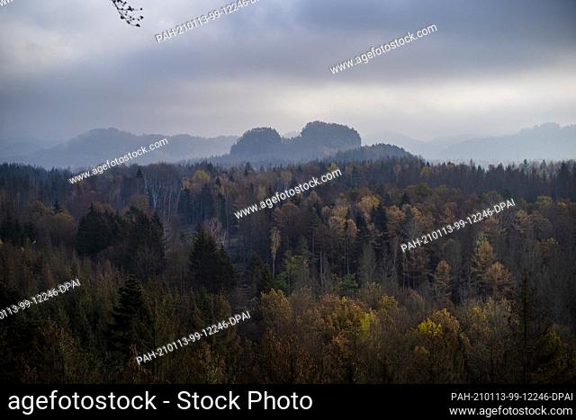 30 September 2017, Saxony, Bad Schandau: Light fog obscures the view into the valley Elbsandsteingebirge from view of the rock gate Kuhstein in the sunset
