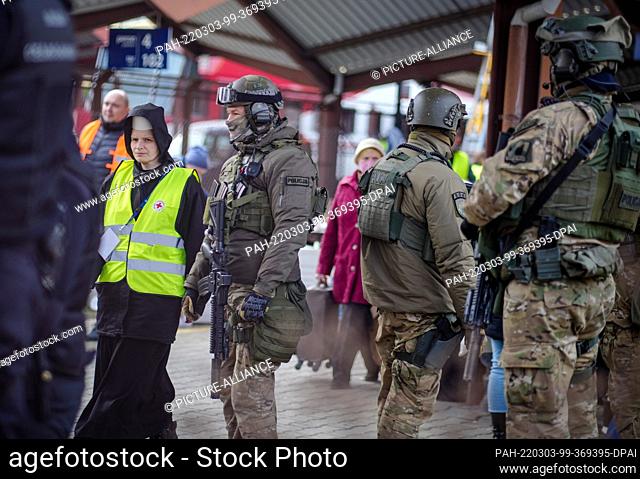 03 March 2022, Poland, Przemysl: A nun walks past heavily armed police at the Przemysl train station near the Ukrainian-Polish border crossing