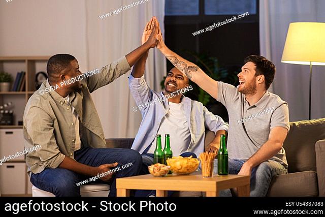male friends with beer making high five at home