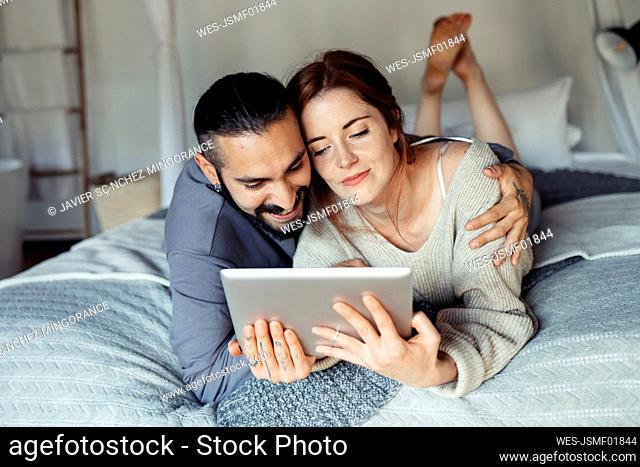 Man embracing woman while using digital tablet at home