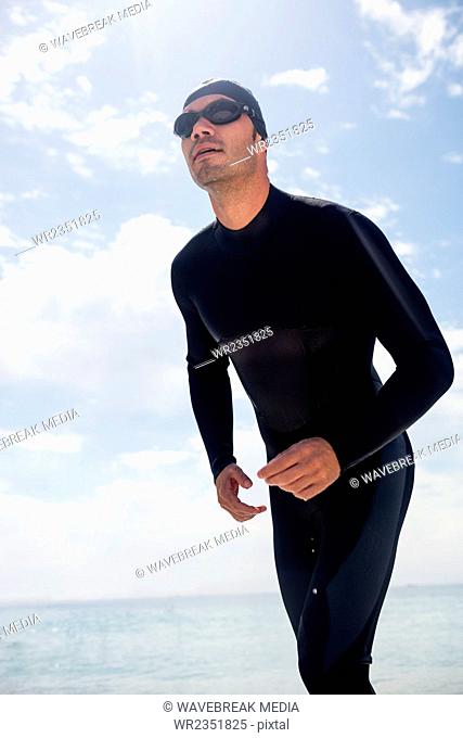Young man in wetsuit ready to run on beach