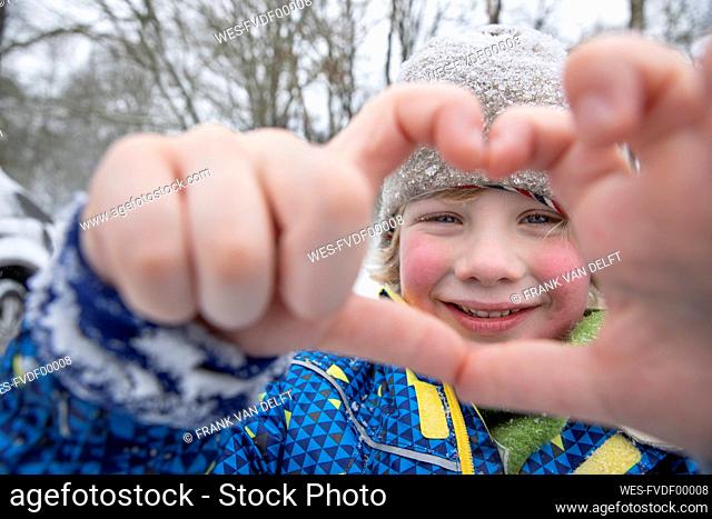 Smiling boy gesturing with hands during winter