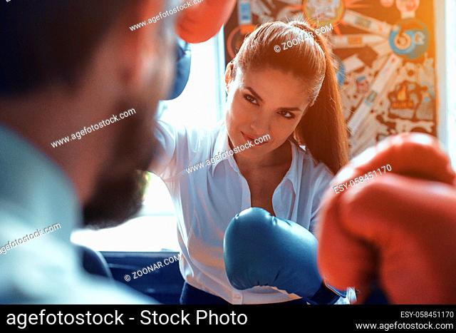 Man and woman in office. Wearing boxing gloves. Compete in business. Fight of genders concept