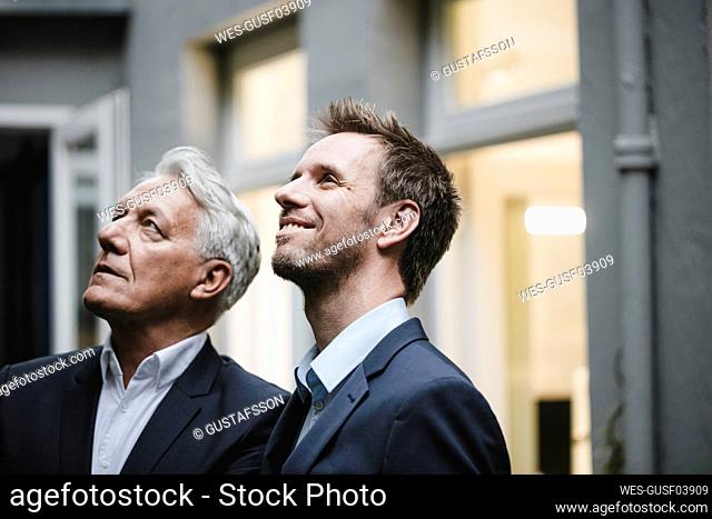 Two successful businessmen, looking at up, smiling