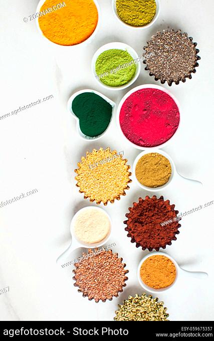 Superfood Smoothie Boosters, various dietary supplements in bowls on white marble background, top view. Alternative medicine, nutritional supplements
