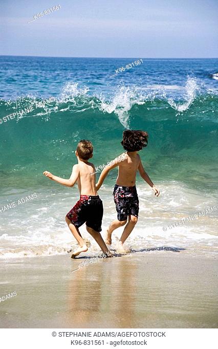 two boys running from a wave
