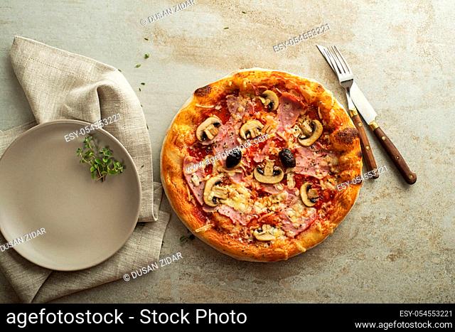 Pizza served with mozzarella cheese, ham, mushrooms and tomato sauce