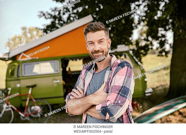 Smiling man in front of van in the nature