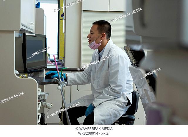 Male dentist using desktop pc in clinic