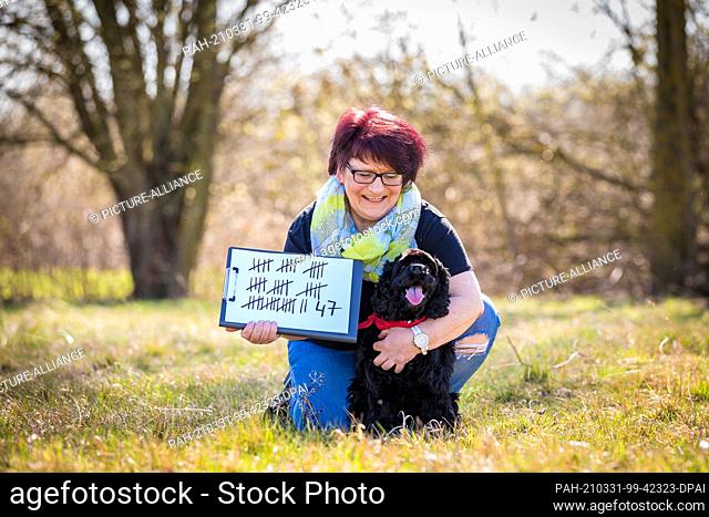 31 March 2021, Lower Saxony, Hanover: Jutta Gaßmann shows a tally after a world record attempt in ""hoop jumping"" with her dog Gil (American Cocker Spaniel...
