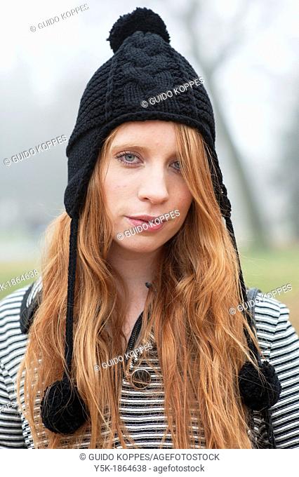 Breda, Netherlands. Young, fashionable and redheaded woman in a city-park