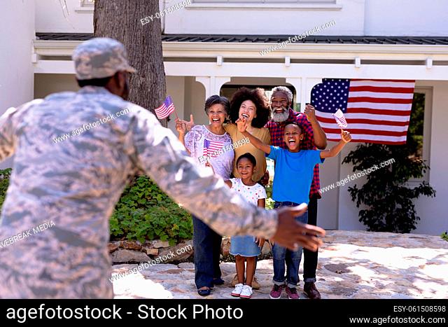Multi-generation mixed race family welcoming an African American man wearing military uniform