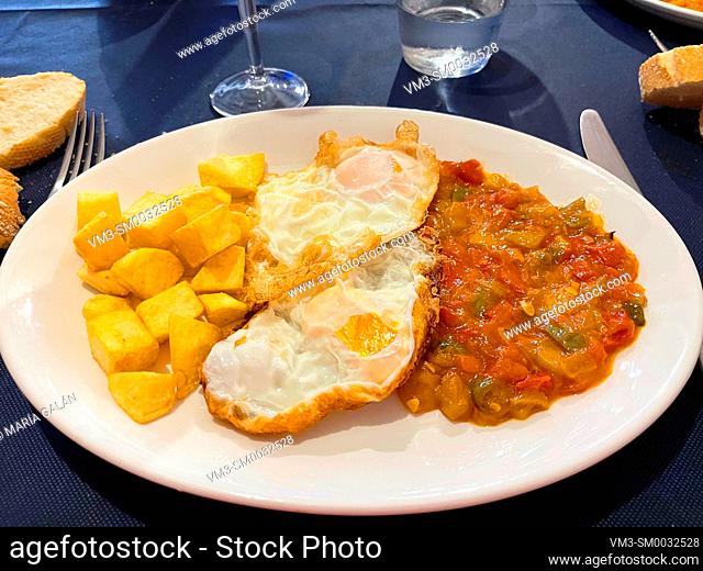 Fried eggs with pisto and fried potatoes. Spain