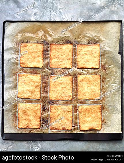 Caramelised pastry squares on baking parchment