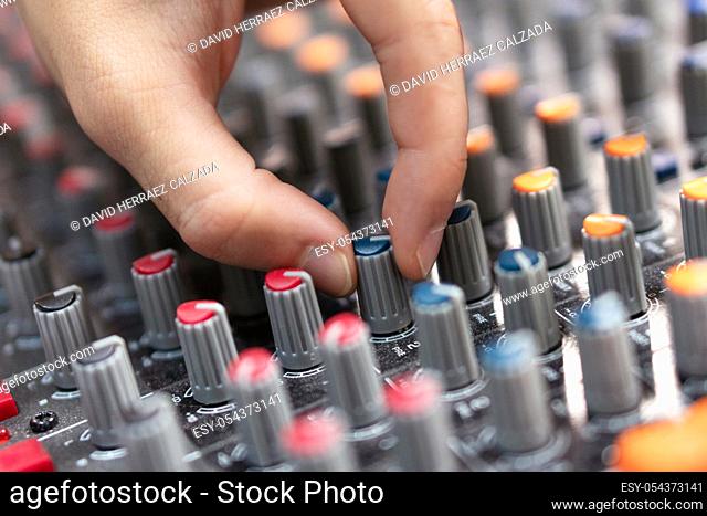 Close-up of a mixing console, hand equalizing audio channels. Professional recording studio. Working in recording studio