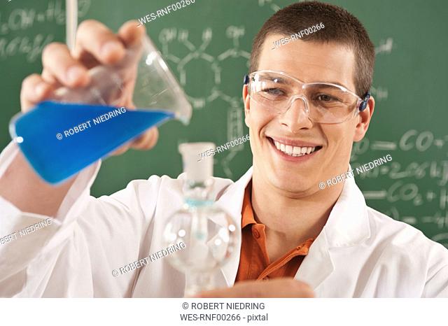 Germany, Emmering, Young man doing experiment, smiling