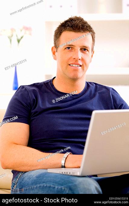 Man sitting on sofa at home and using laptop computer