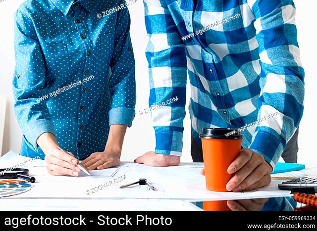 Man and woman together working at design project. Creative teamwork at workspace with construction blueprint and color swatches