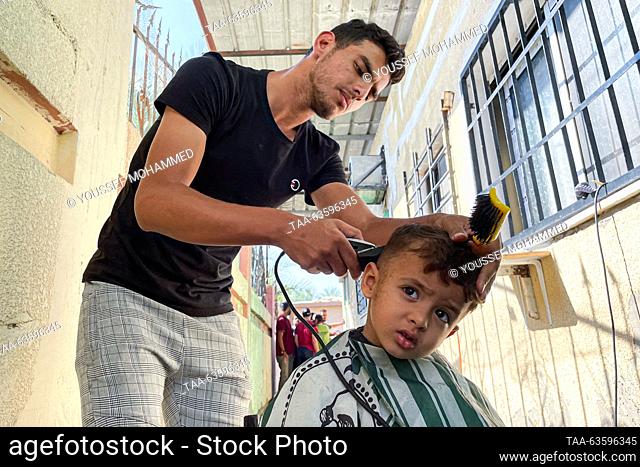 PALESTINIAN TERRITORIES, GAZA STRIP - OCTOBER 16, 2023: A barber cuts the hair of a child who had to leave his house due to the Israeli-Palestinian conflict