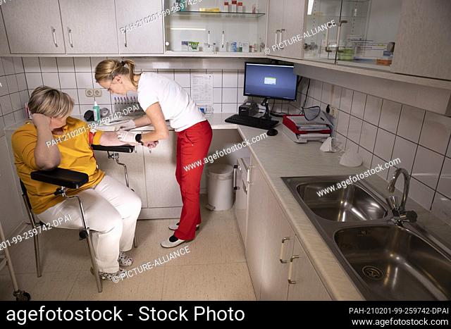 08 December 2020, Mecklenburg-Western Pomerania, Schwerin: A doctor draws blood for tests on a patient in the laboratory of a family practice