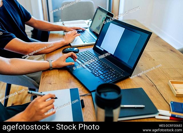 Web designers working while using laptop at office desk