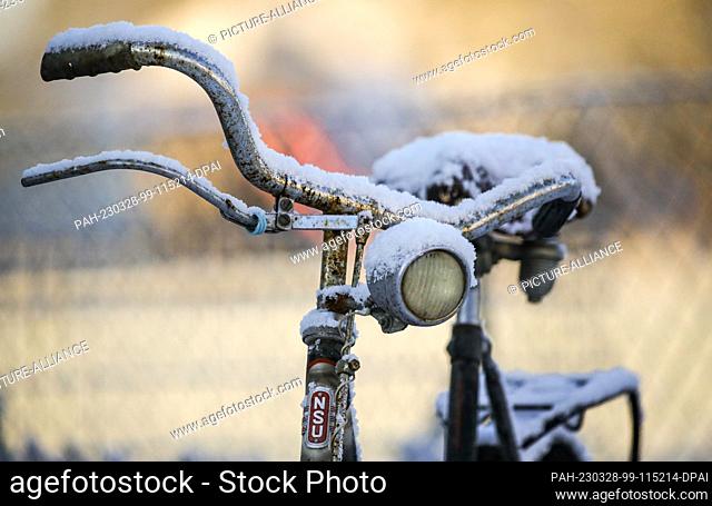 28 March 2023, Baden-Württemberg, Riedlingen: Snow lies on an old bicycle in the morning. During the night it has snowed in Upper Swabia and the Swabian Alb...