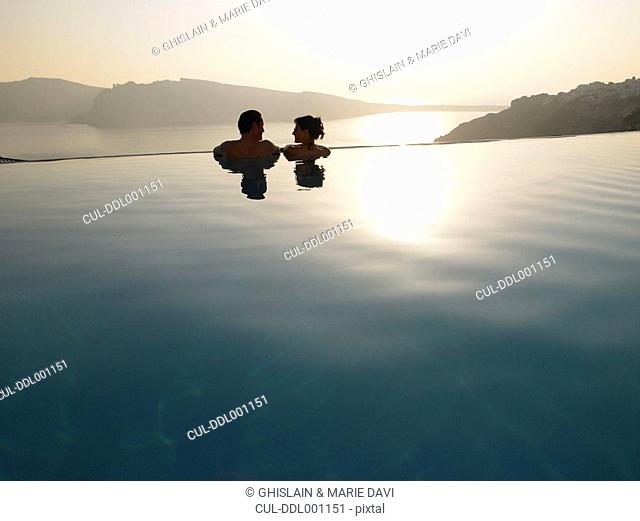 Couple in swimming pool, sunset