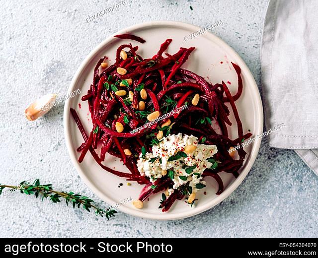Raw beetroot spaghetti salad with soft cheese, nuts, thyme.Vegetable noodles - Fresh Beetroot Noodles with Ricotta and fresh thyme on plate