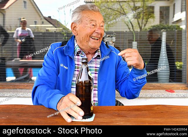 Restful old man (92 years) is sitting on his terrace and chatting animatedly, while one hand rests on a beer bottle, drinking alcohol, beer, beer drinker