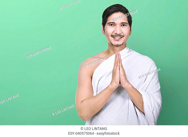 Handsome asian muslim with ihram clothes standing over green background