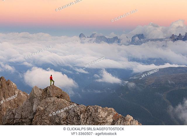 A hiker observes the dusk on the group of Agnèr from the Costabella Ridge, Marmolada group, Dolomites, Moena, Fassa Valley, Trento province, Trentino-Alto Adige