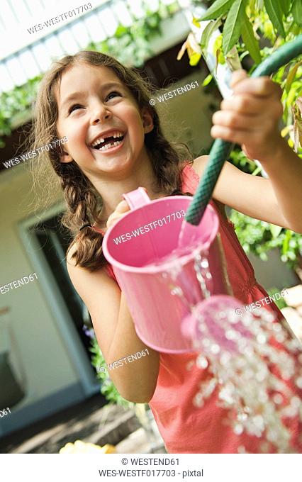 Germany, Bavaria, Girl gardening with watering can, smiling