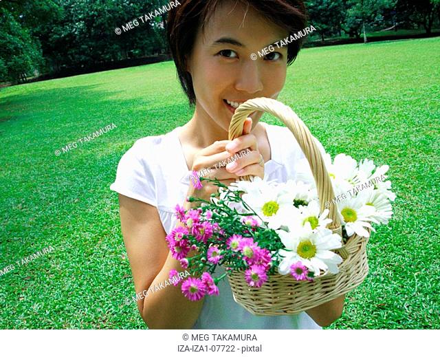 Portrait of a young woman holding a basket of flowers and smiling