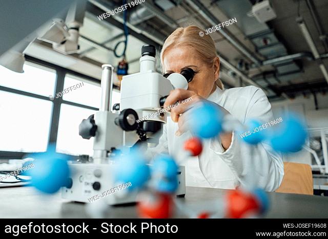 Senior scientist examining with microscope in laboratory