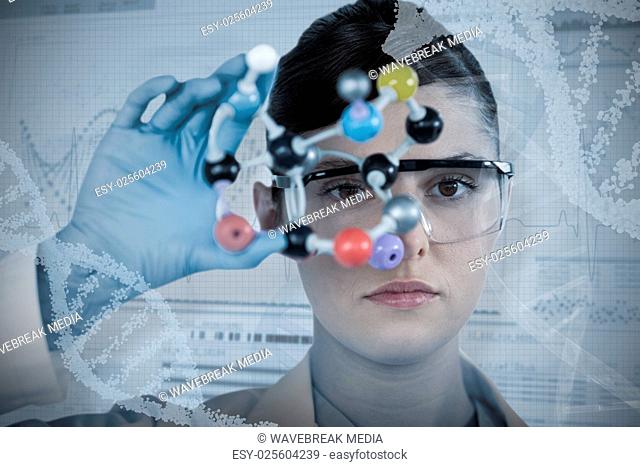 Composite image of portrait of confident female scientist holding molecular model
