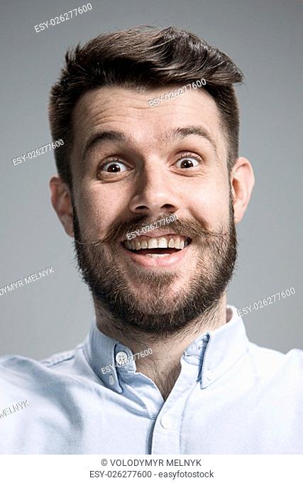 Portrait of young man with shocked facial expression over gray background